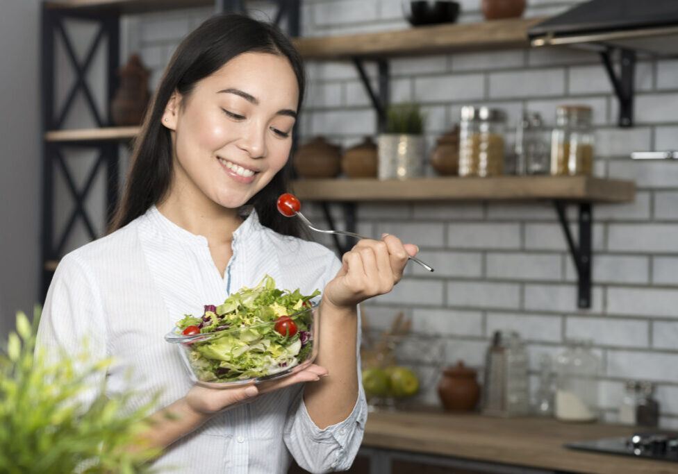 front-view-woman-eating-cherry-tomato-with-green-vegetables